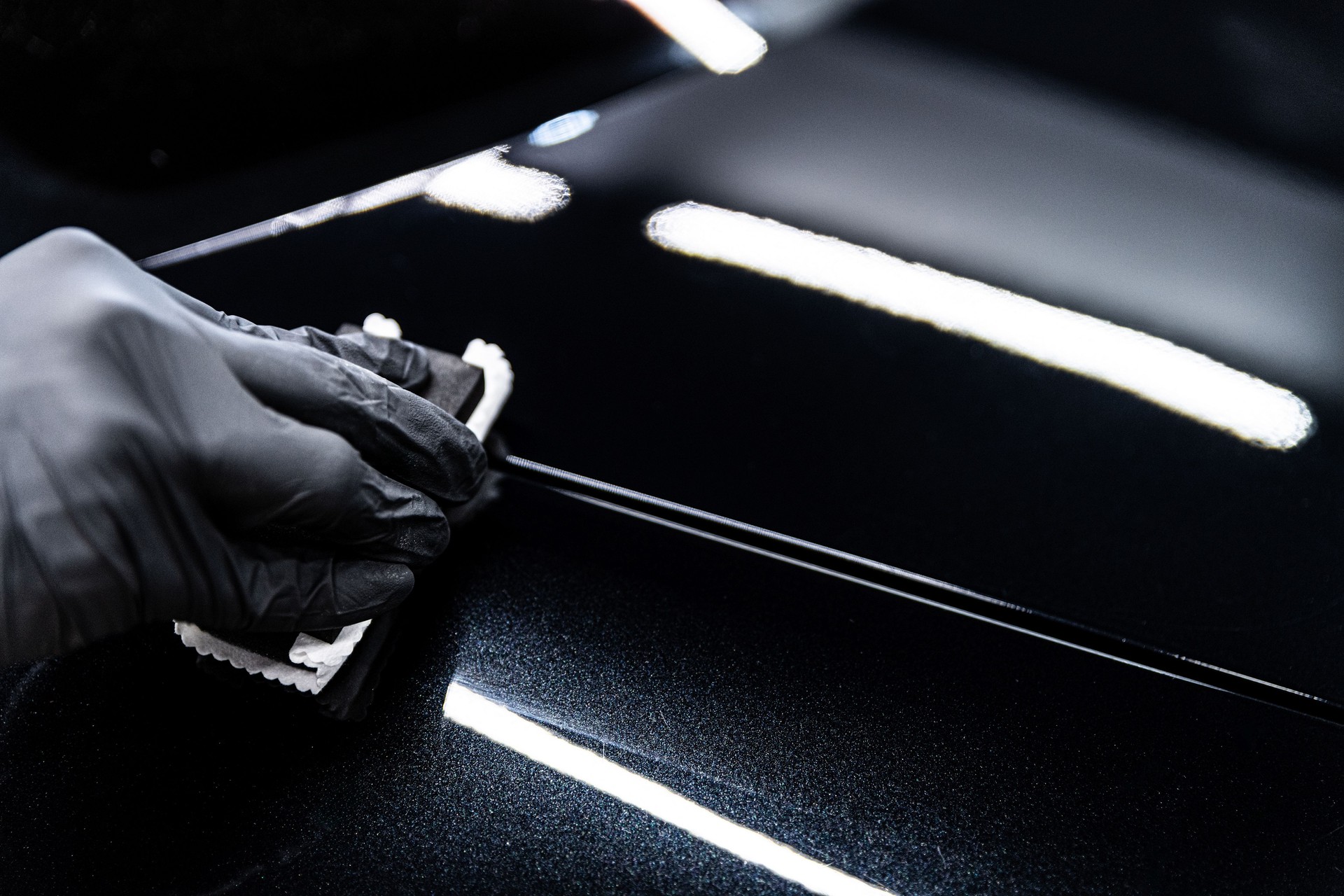 Car wash or detailing studio employee applies ceramic or graphene coating